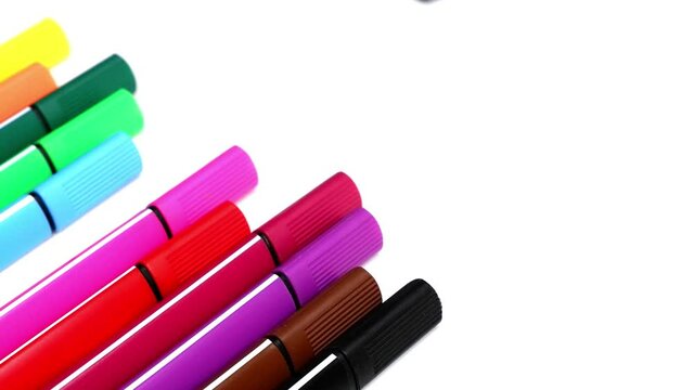 The woman takes a blue marker from a stack of colored marker. Colored markers on a white background.