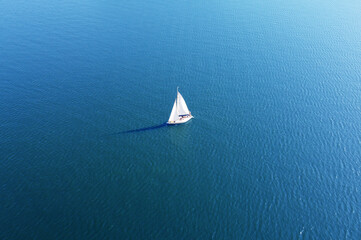 Aerial view of a white yacht with a sail. Ship in the blue sea