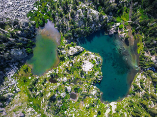 Vertical aerial view from above of two big lakes surrounded by a natural green landscape.