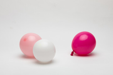 Small balloons in white, pink, and puchisha colors on a white background.