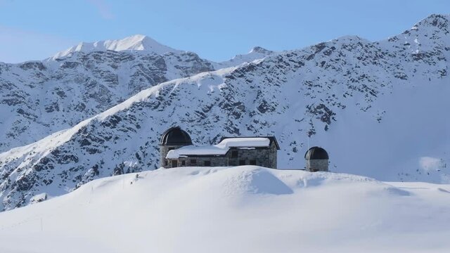 Former Chur astronomical observatory, now closed, on the Arosa-Lenzerheide ski domain, Switzerland, during Winter - aerial parallax view.