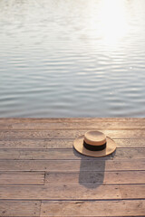 Fototapeta na wymiar Summer hat on the wooden pier by the lake at sunset