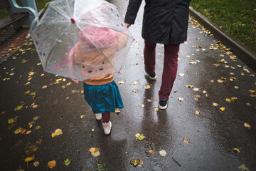 An unrecognizable family walks in a rainy autumn city.