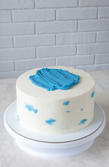 Simple white cake with blue decor on table with copy space