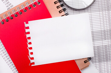 On a light background there are reports, a magnifying glass, brown and red notepads, and a white...