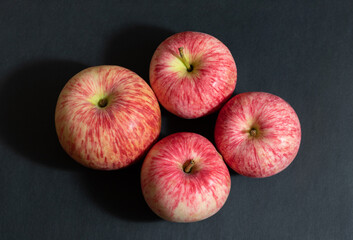 Four red apples on a black background closeup. Striped apples. Juicy fresh ripe fruit. View from above.