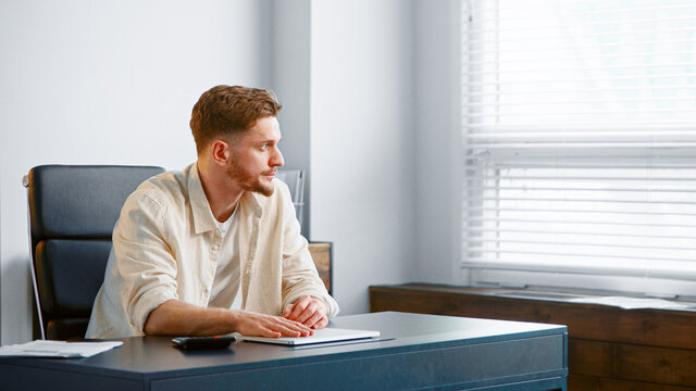 Thoughtful guy manager with beard sums up administrative expenses on calculator