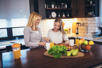 Happy mother and daughter making breakfast at home kitchen and spend time together
