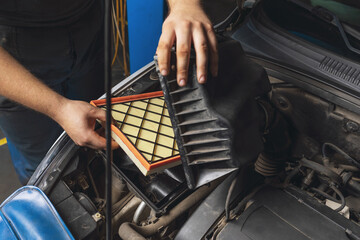 An auto mechanic installs a new engine air filter in the car - obrazy, fototapety, plakaty
