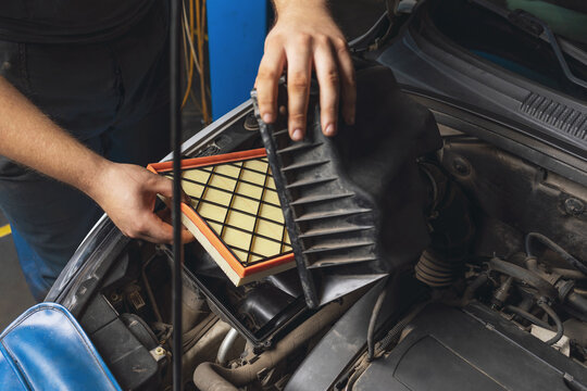 An auto mechanic installs a new engine air filter in the car
