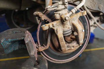 An auto mechanic removed a completely worn out brake pad, a concept on the timely replacement of car parts