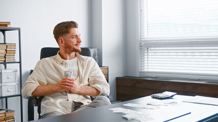 Delighted manager man in yellow shirt looks into white window with cheerful smile
