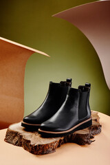Black leather chelsea boots made of genuine leather in classic style on a wooden cut. Close-up....