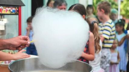 The process of making cotton candy outdoors for children.