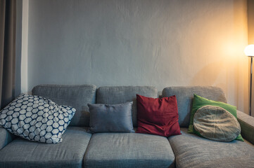 Modern grey fabric sofa with pillows and lighting lamp