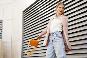 Stylish young businesswoman walking on the city street on sunny day