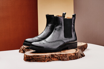 Black leather chelsea boots made of genuine leather in classic style on a wooden cut. Close-up....