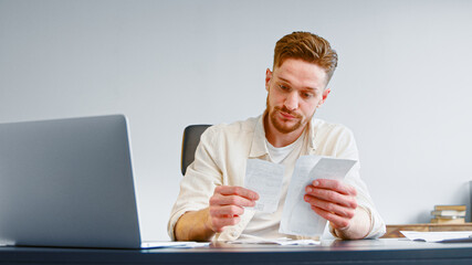 Bearded financial director analyzes paper checks searching for money waste and unexpected expenses...