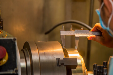 The operator measure thickness of turning brass material part by vernier caliper .