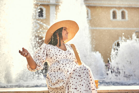 mujer en el centro de sincelejo con  sombrero sonriendo mirando hacia un lado y fuente de agua  en la parte de atras