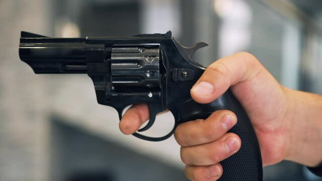 The bandit man is holding a firearm and aiming. The man removes the revolver from the fuse. Multi-charged rifled short-barreled small arms with a rotating drum for shooting