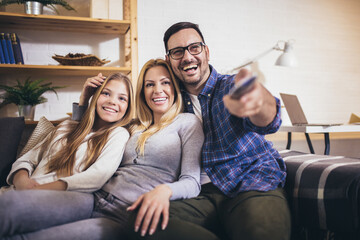 Happy family watching TV together at home and having fun together.