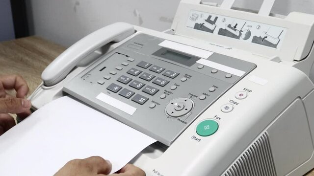 hand man is using a fax machine in the office, equipment for data transmission.