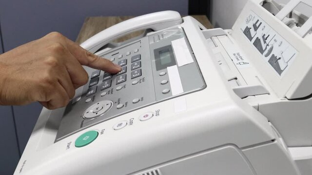 hand man is using a fax machine in the office, equipment for data transmission.