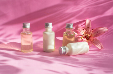 A bottle of cream, lotion, mousse, cleanser, shampoo for skin and hair care. White plastic packaging in a row on a bright pink background decorated with shadows of flowers. Layout of salon products