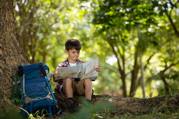 American Little boy child reading map in the forest  trail adventure at summer holiday