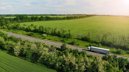 Aerial. Heavy truck driving by the countryside road between fields. View above from drone. © Dmytro