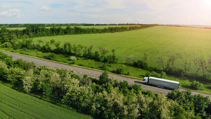 Aerial. Heavy truck driving by the countryside road between fields. View above from drone.