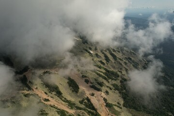 a volcano in clouds and white steam in the early morning. epic and mystical view of the mountain with thick fog around the old volcano