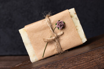 Natural handmade soap on rustic wood podium on wooden background with black concrete wall. Brown...