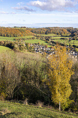 Fototapeta na wymiar The village of Uley tucked in beneath the Cotswold escarpment viewed from Uley Bury, an Iron Age hill fort, Gloucestershire UK