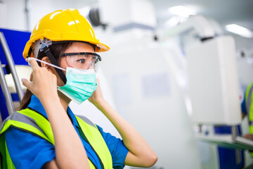 Portrait of Asian worker woman wearing medical face mask in industrial factory. colleague work with...