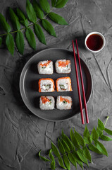 Sushi with salmon on a gray dish with chopsticks, on a concrete gray background top view