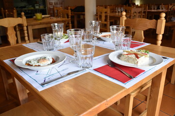 View of restaurant with tables and chairs. Main table with summer dishes, salad, goat roll salad, salmorejo and ratatouille with egg.