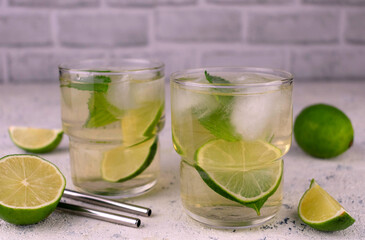 Two glasses with green tea with lime and ice on a white background.