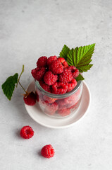 Ripe, juicy raspberries close-up with leaves on a light background