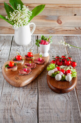 Canapes with sausage, radish, cherry, mozzarella and bread on a light wooden background