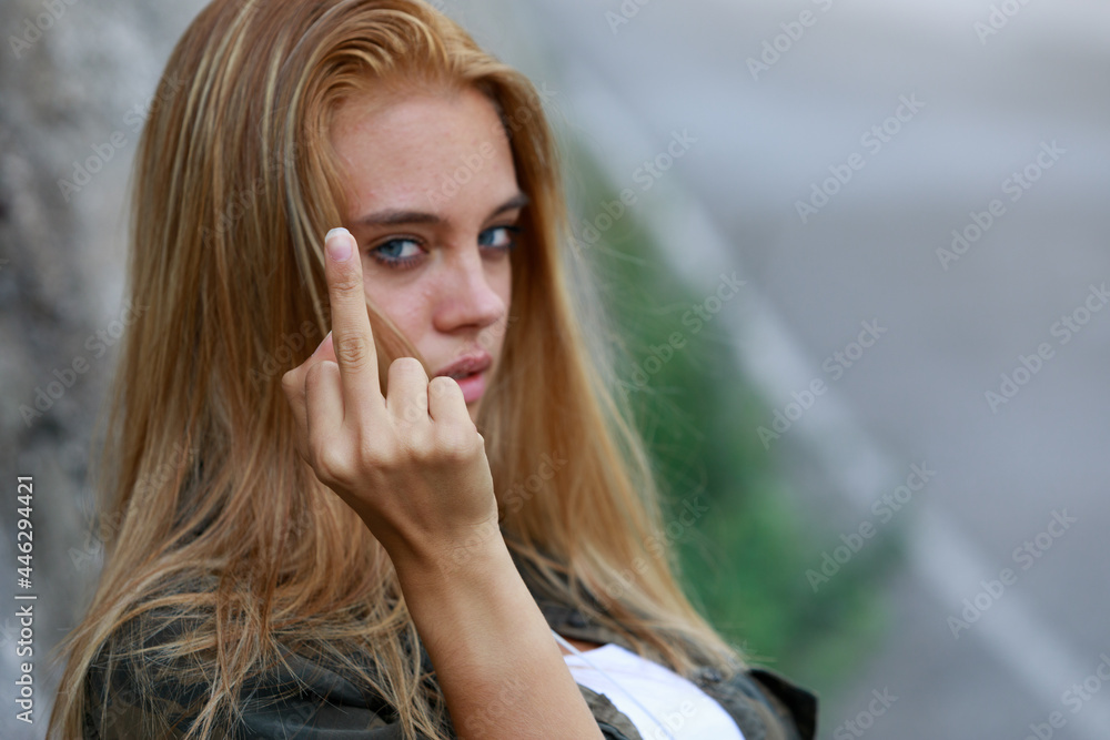 Wall mural rude vindictive young woman giving the middle finger