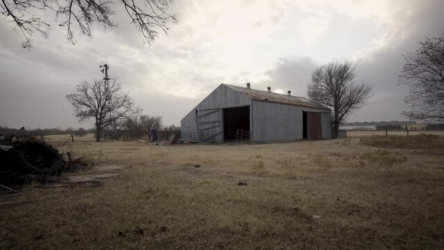 Low Angle Shot of Detriorated Abandon Barn in WIndy FIeld Dystopian Push in Shot 4K