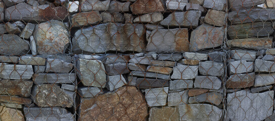 Stone wall background.  Stones behind a metal grid panorama. 