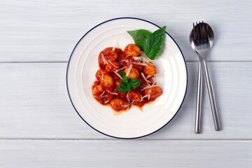 Italian dish, gnocchi with tomato sauce and basil, potato dumplings, on a white wooden table, , no...