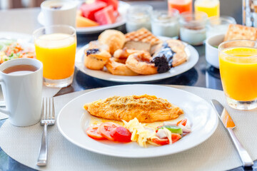 Breakfast Buffet in Luxury Hotel, Omelette and Fresh Desserts, Buns, Croissant. Dining Table with Plate of Delicious Food. Food in Hotel with Plates Full of Food, Orange Juice in Glass and Coffee Cups