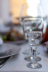 Table with wine glass, plates full serving. Napkins and cutlery. Low light. Selective focus. Ready to party, celebrate. Restaurant services, public catering enterprises. without food. Vertical photo