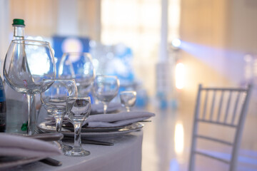 Table and chairs with wine glass, plates full serving. Napkins and cutlery. Low light. Selective focus. Ready to party, celebrate. Restaurant services, public catering enterprises. without food