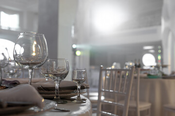 Table with wine glass, plates full serving. Napkins and cutlery. Low light. Selective focus. Ready to party, celebrate. Restaurant services, public catering enterprises