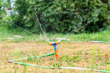 Water sprinkler. Irrigation system - technique of watering in the garden. Lawn sprinkler spraying water over green grass.